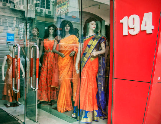Mannequins in traditional indian saris displayed in store window.